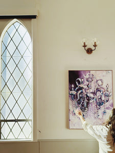 hanging artwork with old world charm and vintage windows. It is a painting by Michelle Schultz of a chandelier in purple and pink