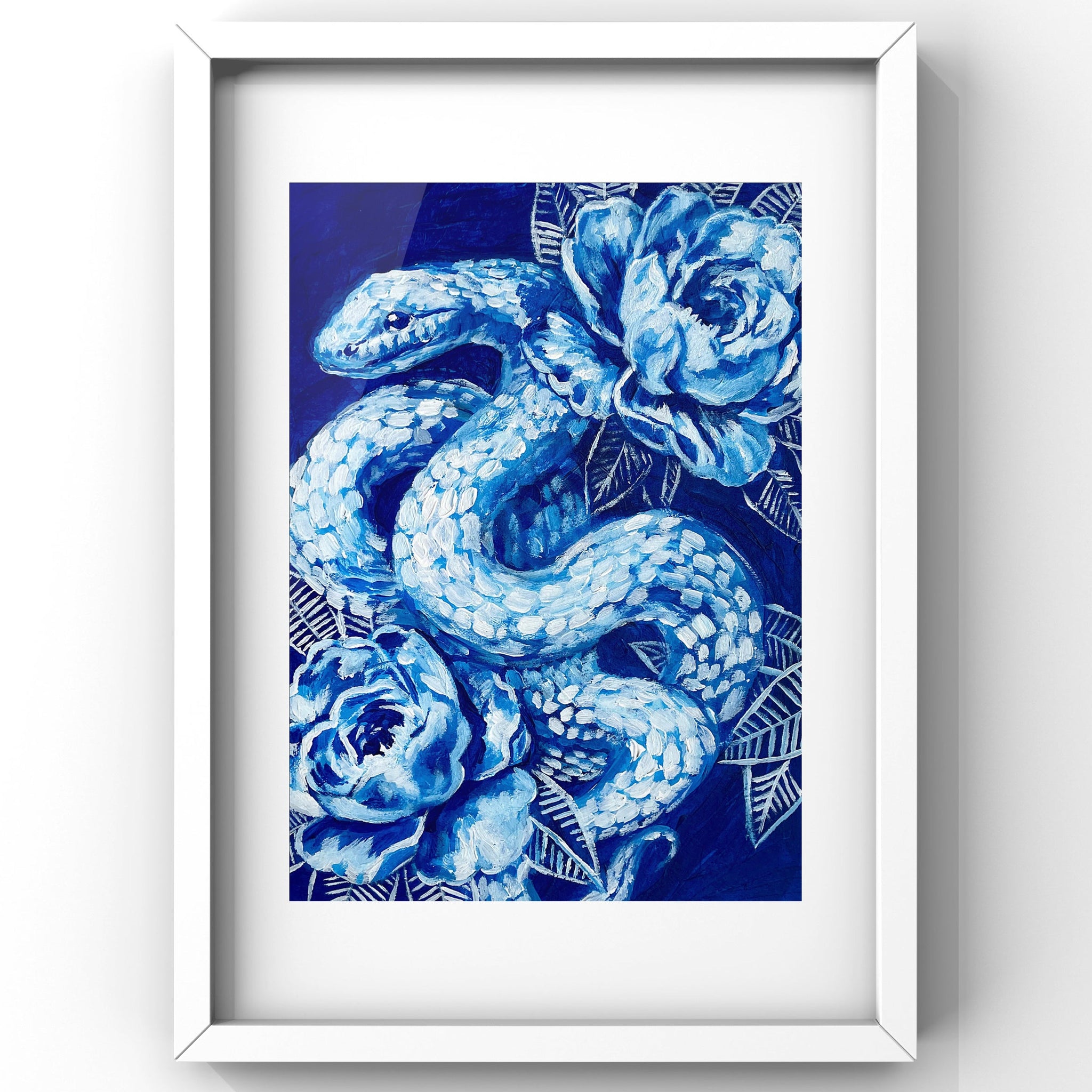 Framed artwork of a blue snake and floral design on a white wall